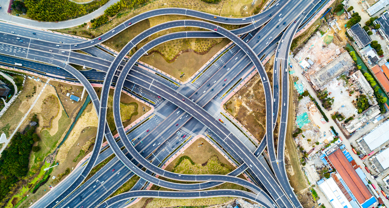 Vue du haut d’un grand échangeur autoroutier à plusieurs niveaux, avec des routes en boucle et des voies qui fusionnent, illustrant l’efficacité du Pegasus TRK300 dans la mesure d’infrastructures routières et urbaines à moyenne échelle pour la planification et la maintenance.